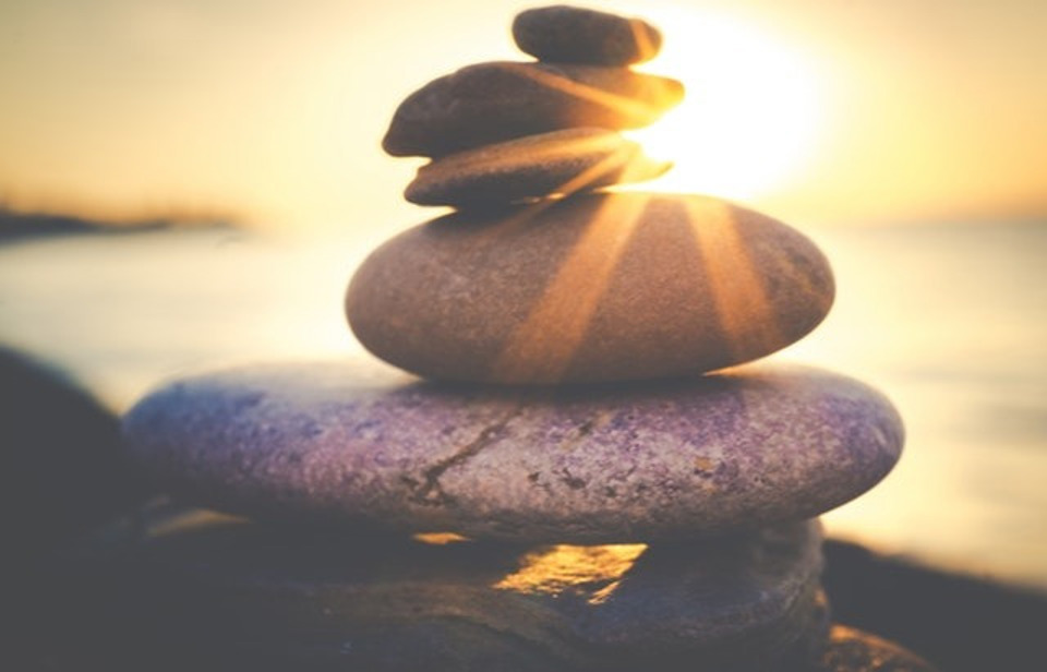 rocks stacked in front of sun