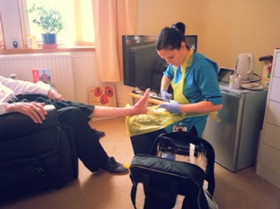 nurse looking at patients foot whilst at home