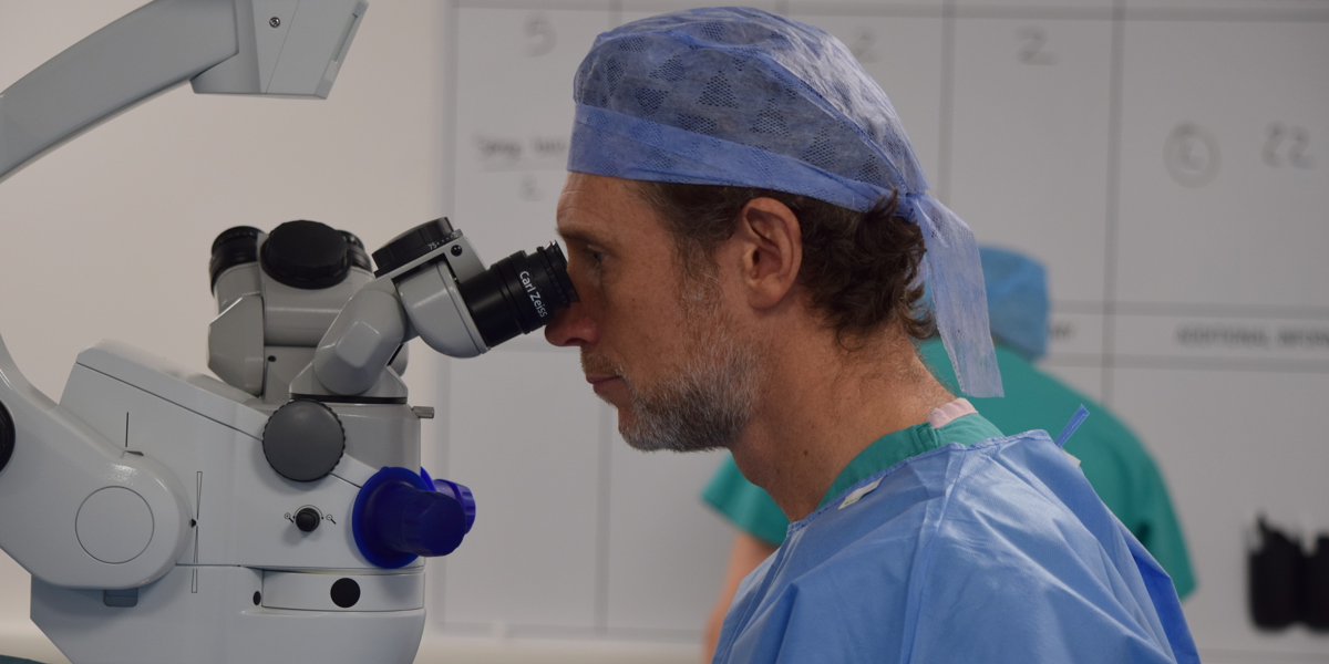 surgeon looking through microscope